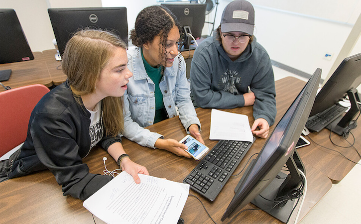 Three students looking at a computer screen